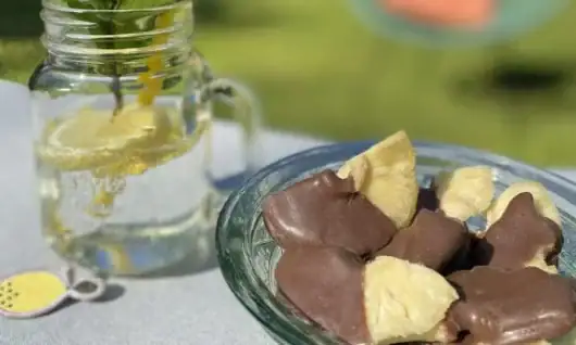 Köstliche Valio Milchschokolade mit Vanillegeschmack auf einem Teller und kaltes Wasser mit Zitronen.