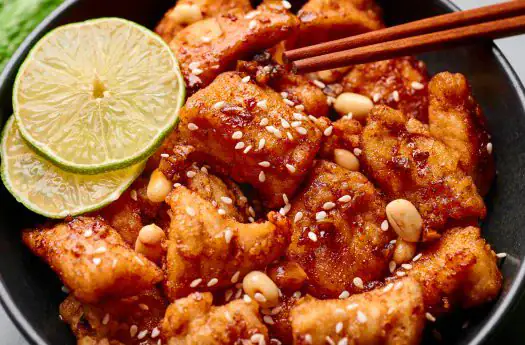 Knuspriges Tofu mit Limettenscheiben, Sesam und Erdnüssen in einer asiatischen Pfanne. Perfekt für v.