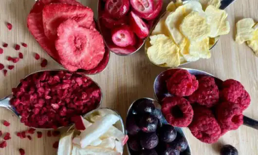 Frisches Beeren- und Fruchtmischung, ideal für Desserts und Snacks, auf Holzplatte präsentiert.
