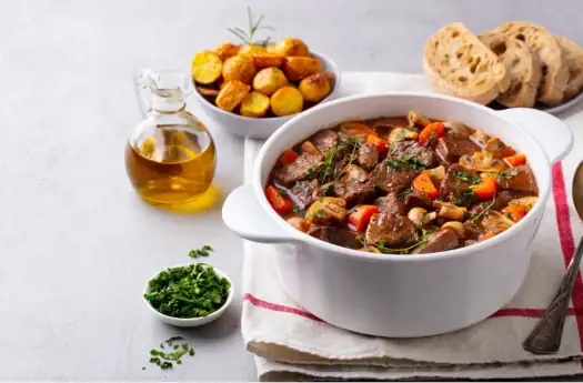 Herzhaftes Rindfleisch-Gulasch mit Gemüse und frischem Brot, ideal für kalte Tage.
