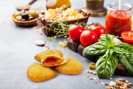 Frische Tomaten, Basilikum und Käse auf einem Holzbrett mit Snacks und Getränken.